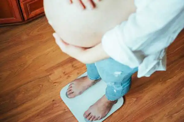 Image of woman weighing herself and experiencing weight gain through pregnancy Warminster